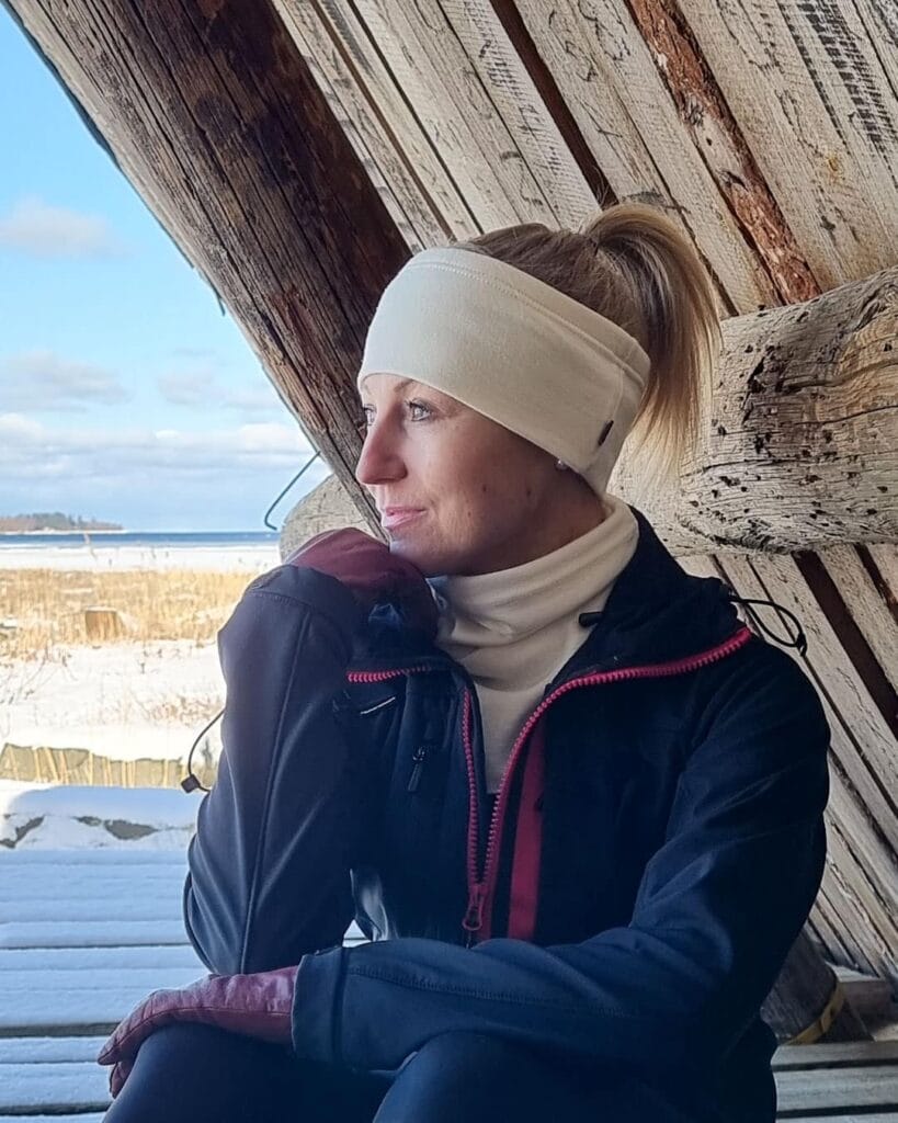 Naisten luonnonvalkoinen merinovillapanta ja -tuubikauluri. Vaaleahiuksisella ulkoilevalla naisella, lähikuva.