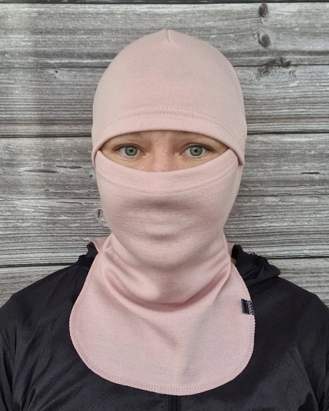 Aikuisten vaaleanpunainen merinovilla kypärähuppu (balaclava), naisen päässä edestä.