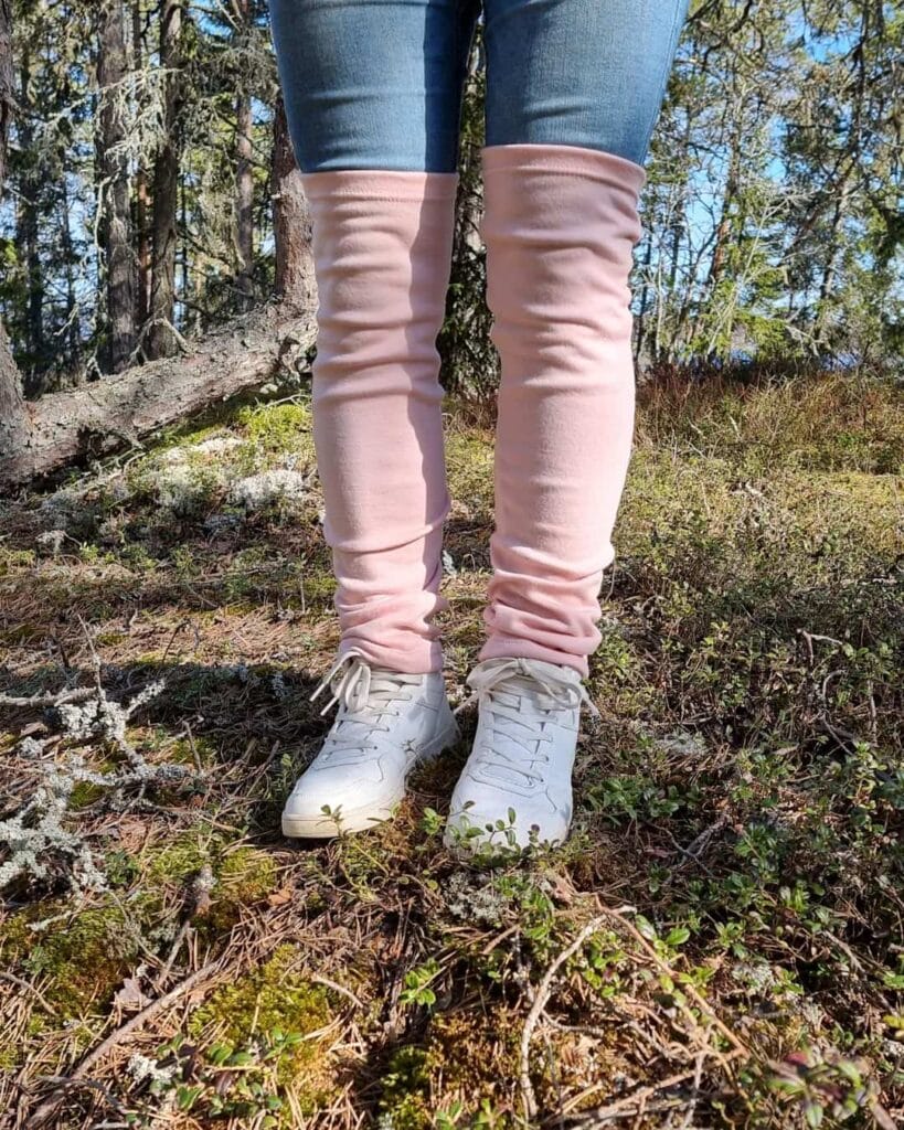 Pitkät merinovilla säärystimet, valkoisten lenkkareidein kanssa naisen jalassa, polven yli nostettuna.