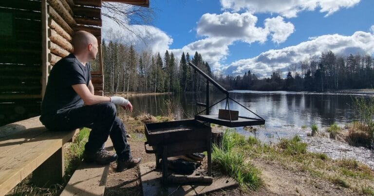 Merino t-paita ulkoiluun ja arkeen, miehen päällä nuotiolla, sivusta päin kuvattuna.