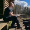 Miesten tummanharmaa merinovilla t-paita, miehen päällä laavulla, sivusta kuvattuna.
