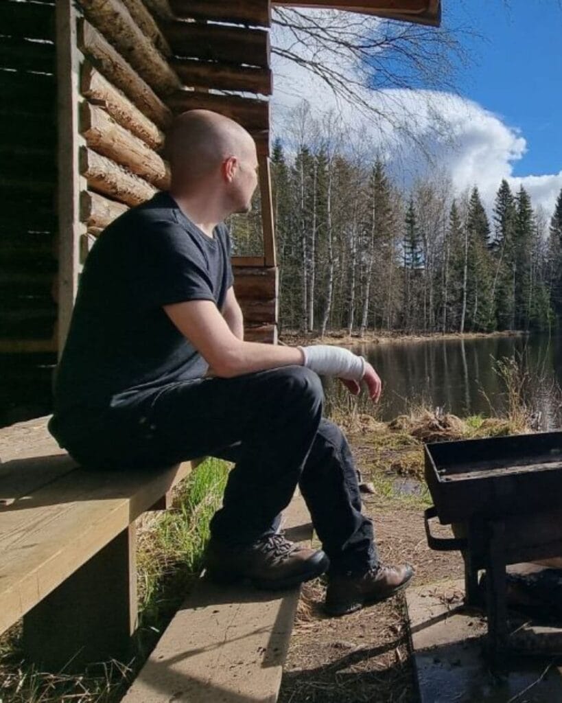 Miesten tummanharmaa merinovilla t-paita, miehen päällä laavulla, sivusta kuvattuna.