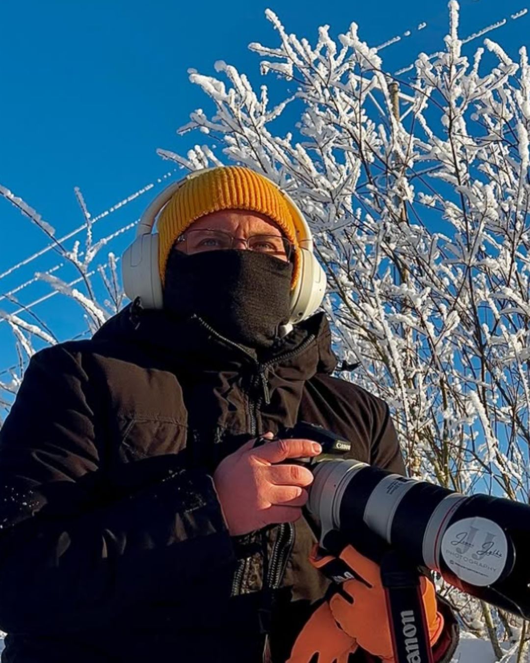 Aikuisten tummanharmaa merinovilla kypärähuppu (balaclava) miehen päässä, pipon alla. Kasvot suojattuna.