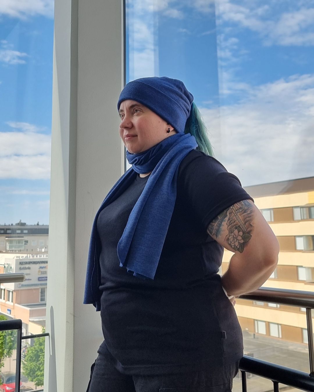 Naisten musta merinovilla t-paita, vihreähiuksisella naisella rappukäytävässä.