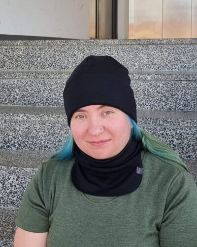 Naisten musta merinovillapipo ja -tuubikauluri vihreähiuksisella naisella. Lähikuva edestä.