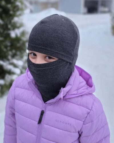 Lasten tummanharmaa merinovilla kypärämyssy (balaclava), tytön päässä kypärämyssy kasvojen suojaksi vedettynä.