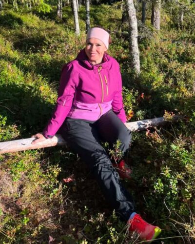 Naisten vaaleanpunainen merinovillapanta. Naisten vaaleanpunainen merinovillapanta ulkoilevan naisen päässä. Kuva edestä.