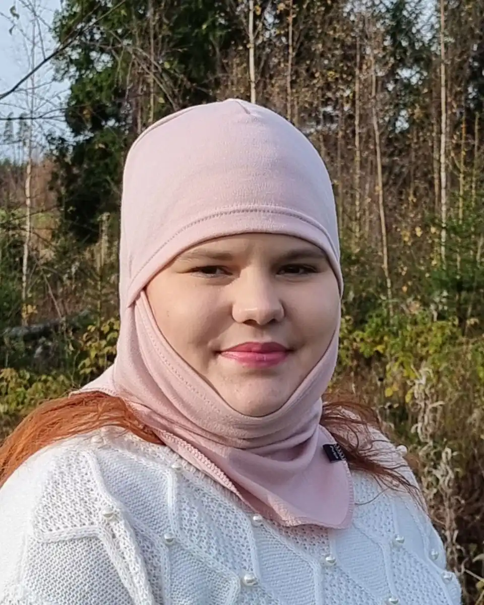 Aikuisten vaaleanpunainen merinokypärämyssy kasvosuojalla (balaclava). Lähikuva kypärämyssy naisen päässä, kasvot näkyvissä.
