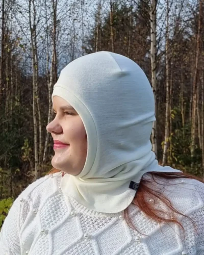 Aikuisten luonnonvalkoinen merinovilla kypärämyssy. Lähikuva kypärämyssystä naisen päässä sivusta kuvattuna.