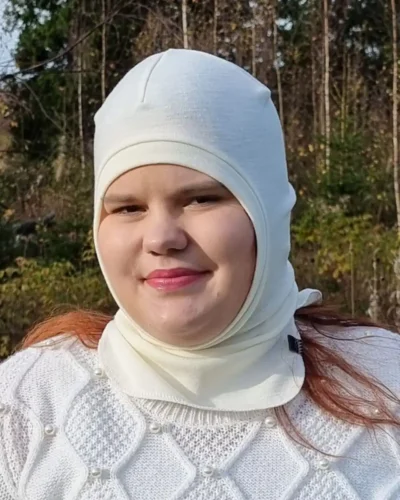 Aikuisten luonnonvalkoinen merinovilla kypärämyssy. Lähikuva kypärämyssystä naisen päässä.