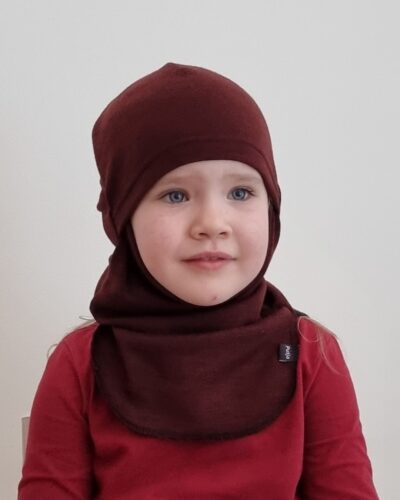 Lasten rubiininpunainen merinokypärämyssy kasvosuojalla (kommandopipo) pienen tytön päässä. Lähikuva edestä.