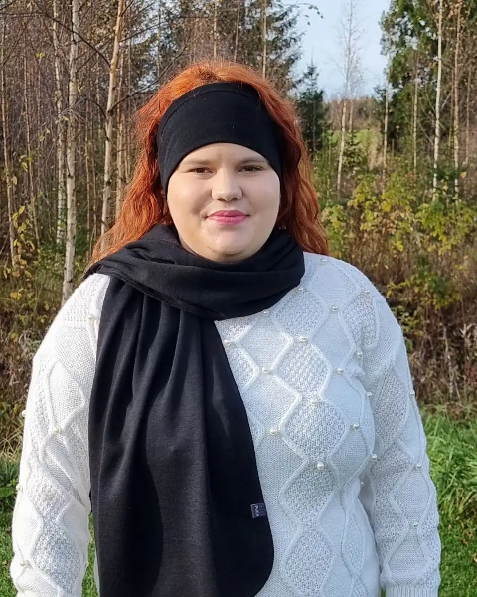 Iso musta merinovilla kaulahuivi (hartiahuivi). Lähikuva punatukkaisesta naisesta, jolla musta merinokaulahuivi kaulallaan.